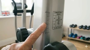 A finger pointing to a measurement scale and a printed guide diagram showing the recommended spinal alignment and lumbar angle degrees on fitness equipment.