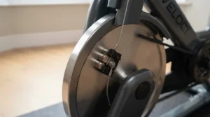 Side profile of an indoor cycling bike focusing on the weighted flywheel for a smooth pedalling motion.