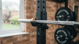 Adjustable J-cups and safety spotter arms fitted to a space-saving wall-mounted power rack.